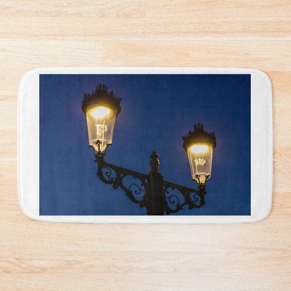 Item preview, Ornate Vintage Double Street Lamp Glowing at Dusk Against Deep Blue Evening Sky designed and sold by Nmallia.