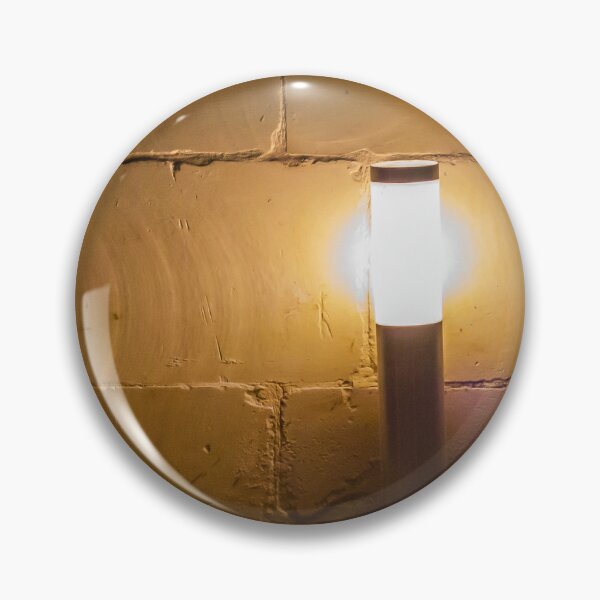 Item preview, Warm Outdoor Bollard Light Casting Soft Glow Against Textured Brick Wall At Night designed and sold by Nmallia.