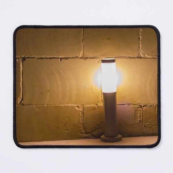 Item preview, Warm Outdoor Bollard Light Casting Soft Glow Against Textured Brick Wall At Night designed and sold by Nmallia.