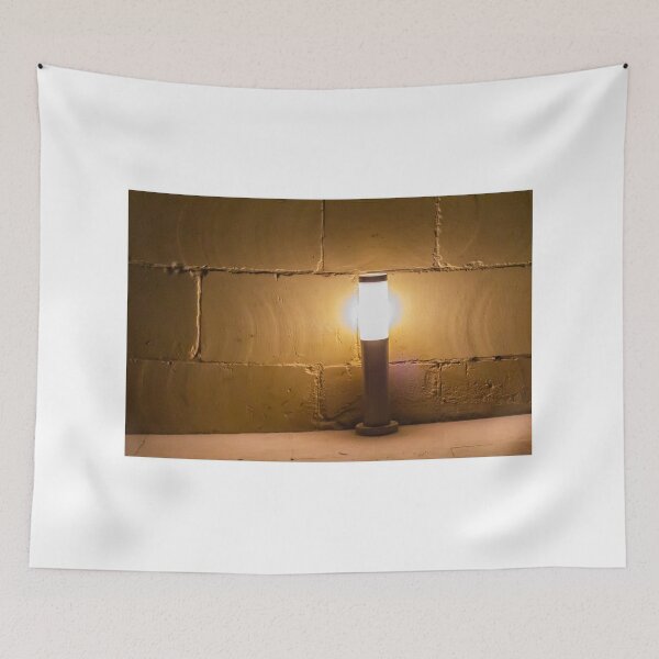 Item preview, Warm Outdoor Bollard Light Casting Soft Glow Against Textured Brick Wall At Night designed and sold by Nmallia.