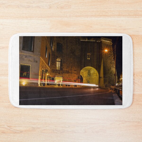 Item preview, Night Light Trails Through Historic Stone Archway On Curved Urban Street Under Warm Lighting designed and sold by Nmallia.