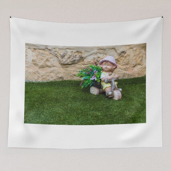 Item preview, Whimsical Garden Figurine Of Girl On Wooden Tricycle With Flowers Against Stone Wall designed and sold by Nmallia.