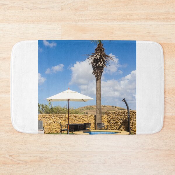 Item preview, Sunny Resort Pool With Palm Tree, Umbrella and Lounge Chairs Overlooking Stone Wall and Blue Sky designed and sold by Nmallia.
