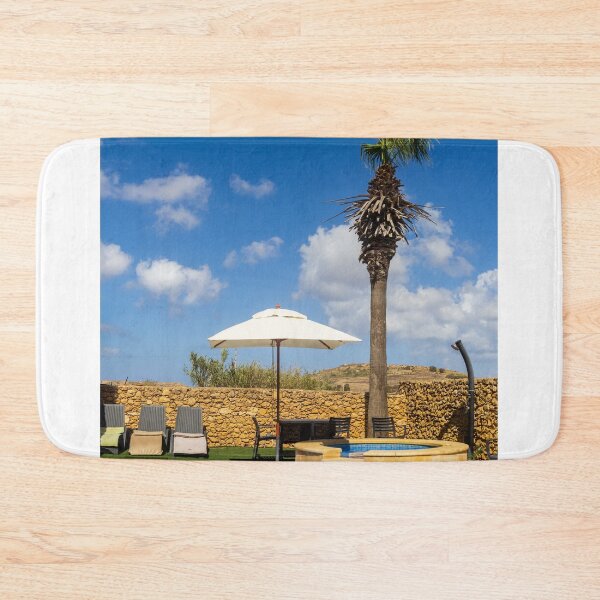 Item preview, Sunny Resort Pool With Palm Tree, Umbrella and Lounge Chairs Overlooking Stone Wall and Blue Sky designed and sold by Nmallia.