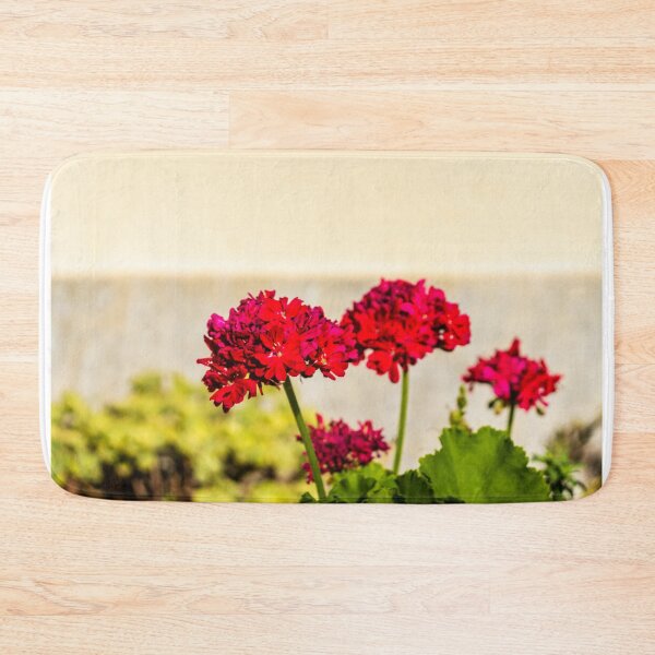 Item preview, Close-up red geranium flowers in a sunny garden with green leaves and soft background bokeh designed and sold by Nmallia.