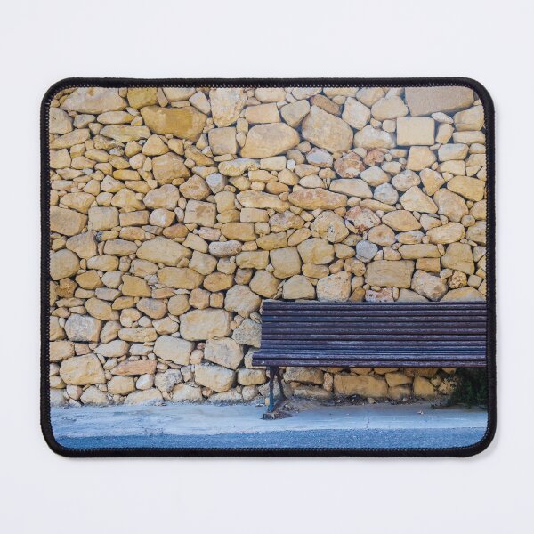Item preview, Weathered Wooden Bench Against Rustic Dry Stone Wall On Quiet Sunlit Street designed and sold by Nmallia.