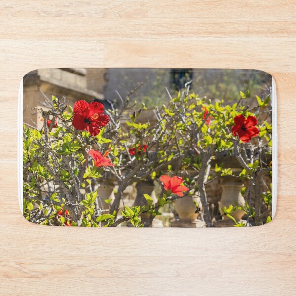 Item preview, Red Hibiscus Flowers Blooming On A Garden Hedge With Stone Balustrade In Sunny Light designed and sold by Nmallia.