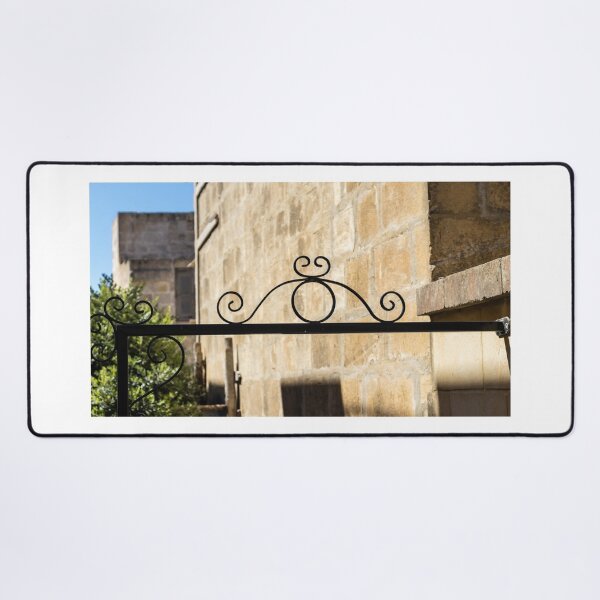 Item preview, Wrought Iron Decorative Gate Bracket With Scrollwork Against Sunlit Stone Wall in Historic Courtyard designed and sold by Nmallia.