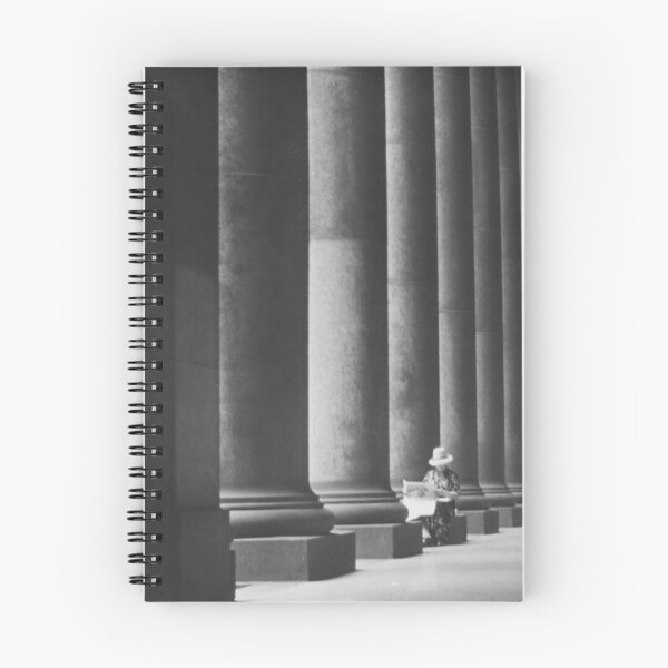 Item preview, Woman reading newspaper while seated beside building columns black and white vintage art print photograph designed and sold by Astrid Arkhangelsky.