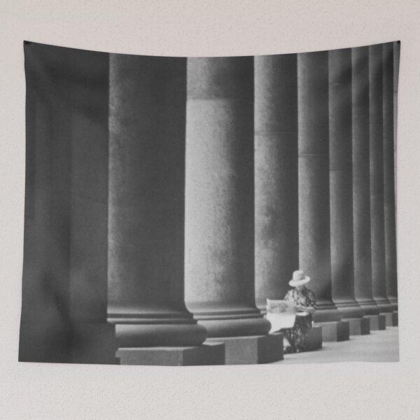 Item preview, Woman reading newspaper while seated beside building columns black and white vintage art print photograph designed and sold by Astrid Arkhangelsky.