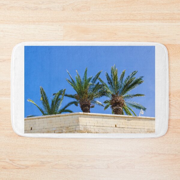 Item preview, Three Palm Trees Rising Above A Pale Stone Wall Under A Clear Blue Sky On A Sunny Day designed and sold by Nmallia.