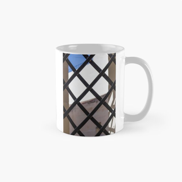 Item preview, Black Metal Lattice Fence With Diamond Pattern Framing Bright Urban Building And Blue Sky Background designed and sold by Nmallia.