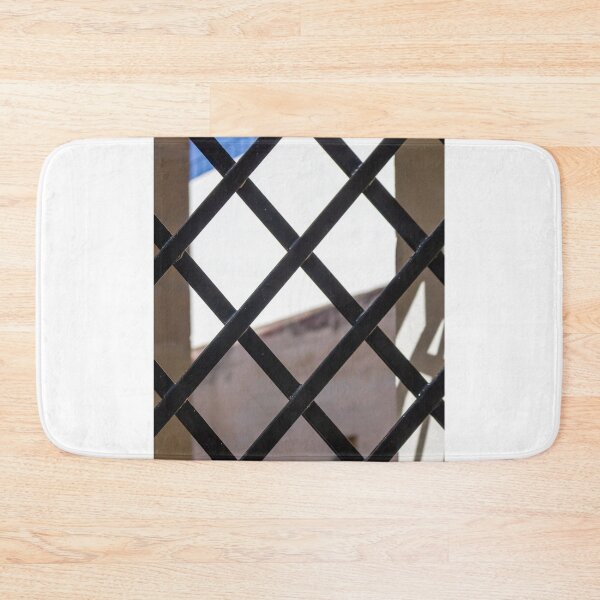 Item preview, Black Metal Lattice Fence With Diamond Pattern Framing Bright Urban Building And Blue Sky Background designed and sold by Nmallia.