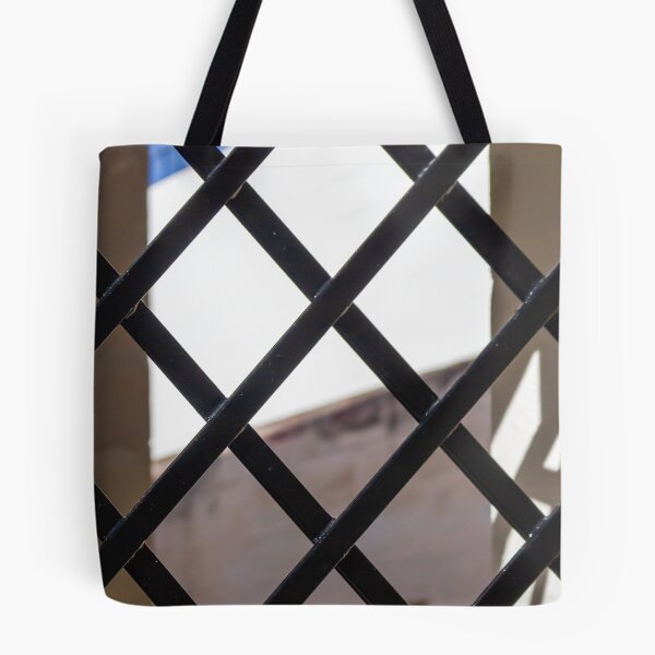 Item preview, Black Metal Lattice Fence With Diamond Pattern Framing Bright Urban Building And Blue Sky Background designed and sold by Nmallia.