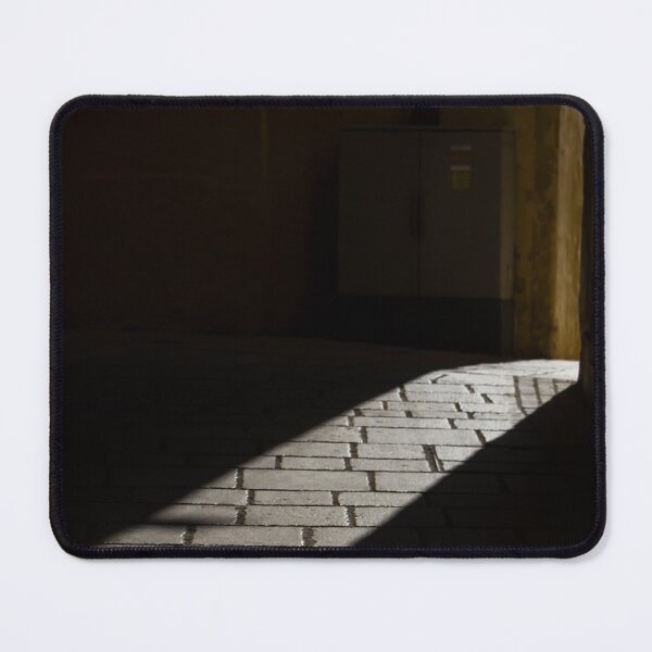 Item preview, Diagonal Sunlight on Cobblestone Alleyway Casting Dramatic Shadow in Narrow Urban Passage designed and sold by Nmallia.