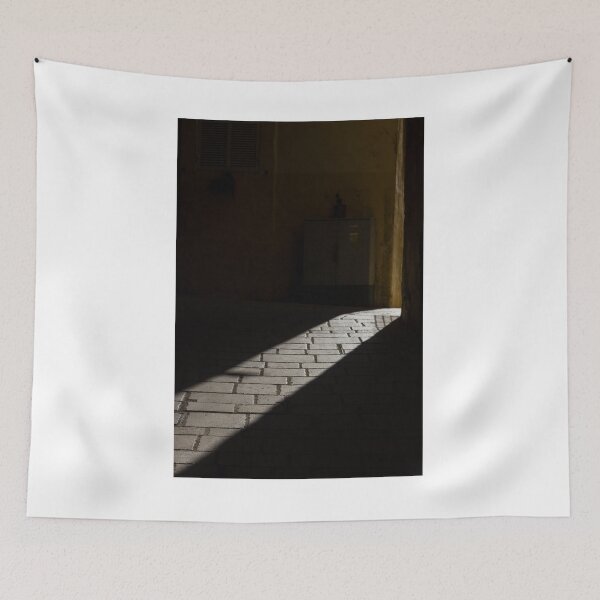 Item preview, Diagonal Sunlight on Cobblestone Alleyway Casting Dramatic Shadow in Narrow Urban Passage designed and sold by Nmallia.