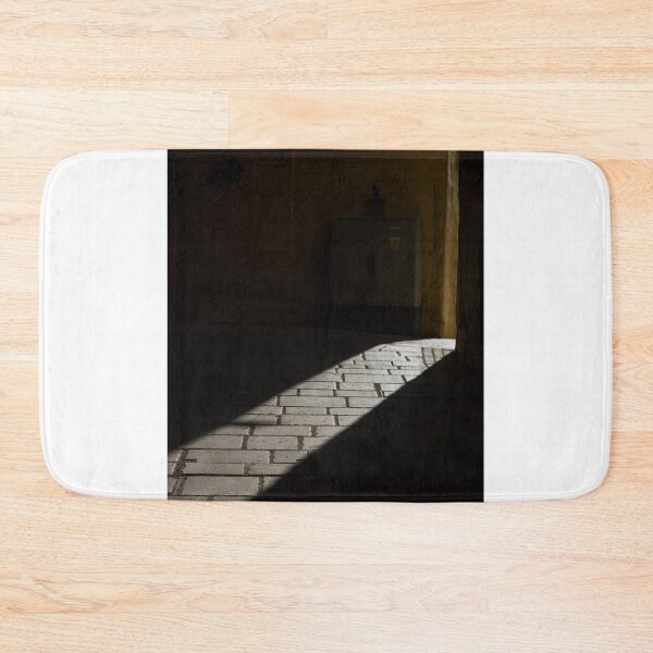 Item preview, Diagonal Sunlight on Cobblestone Alleyway Casting Dramatic Shadow in Narrow Urban Passage designed and sold by Nmallia.