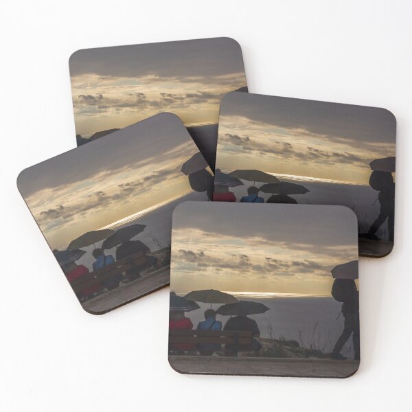 Item preview, Silhouettes With Umbrellas Sitting on Cliff Bench Overlooking Sea at Moody Sunset designed and sold by Nmallia.