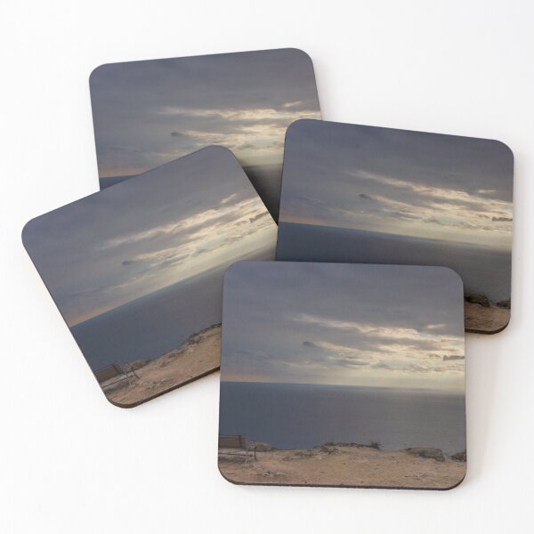 Item preview, Solitary Bench Overlooking Calm Ocean Horizon Under Dramatic Sunset Clouds On Rocky Cliff designed and sold by Nmallia.