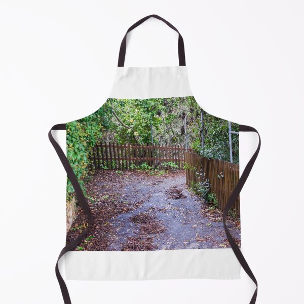 Item preview, Leaf-Covered Garden Path With Wooden Fence Curving Through Lush Greenery In Autumn designed and sold by Nmallia.