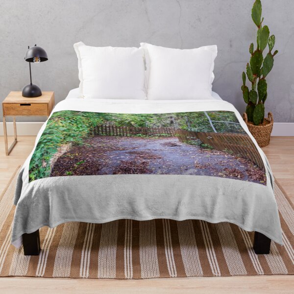 Item preview, Leaf-Covered Garden Path With Wooden Fence Curving Through Lush Greenery In Autumn designed and sold by Nmallia.