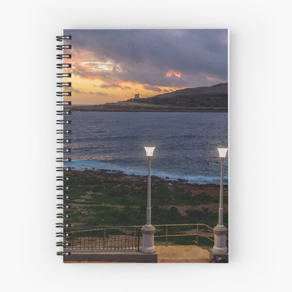 Item preview, Coastal Sunset Over Rocky Shoreline With Lit Lampposts and Distant Headland at Dusk designed and sold by Nmallia.