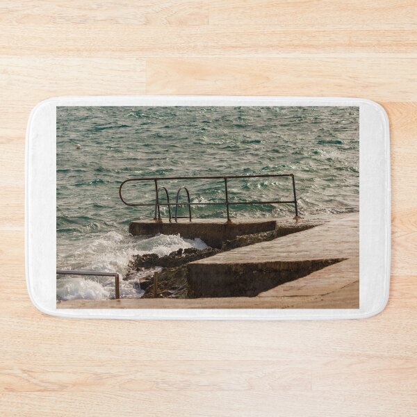 Item preview, Rusty Handrail And Concrete Pier With Ladder Beside Choppy Sea Waves At Coastline designed and sold by Nmallia.