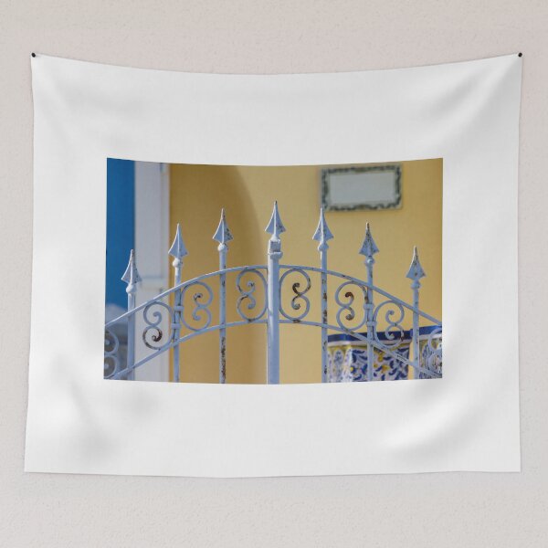 Item preview, Sunlit Ornate Wrought Iron Gate With Rust Patina Against Yellow Wall and Blue Ceramic Planter designed and sold by Nmallia.