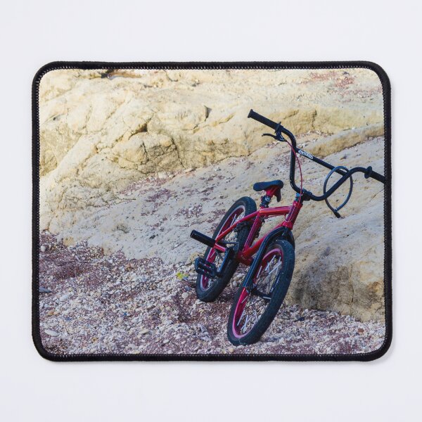 Item preview, Red BMX Bicycle Leaning on Rocky Beach Shoreline Near Sandstone Cliffs on Sunny Day designed and sold by Nmallia.