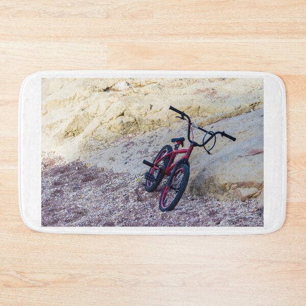 Item preview, Red BMX Bicycle Leaning on Rocky Beach Shoreline Near Sandstone Cliffs on Sunny Day designed and sold by Nmallia.