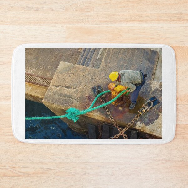 Item preview, Dock Worker Securing Green Mooring Rope To Rusty Bollard On Concrete Pier At Harbor designed and sold by Nmallia.