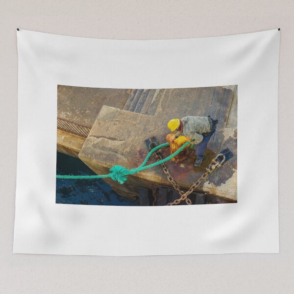 Item preview, Dock Worker Securing Green Mooring Rope To Rusty Bollard On Concrete Pier At Harbor designed and sold by Nmallia.