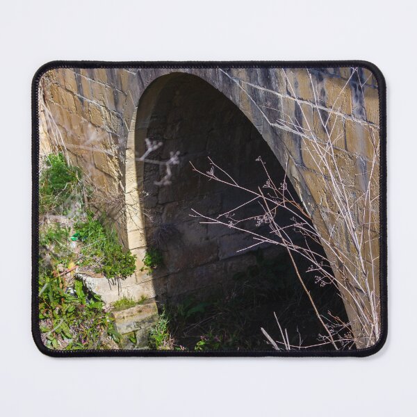 Item preview, Old Stone Arch Bridge With Dark Tunnel Entrance Surrounded by Overgrown Vegetation designed and sold by Nmallia.