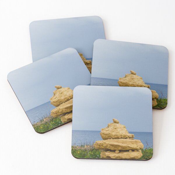 Item preview, Stacked Coastal Rocks Beside Calm Sea Under Cloudy Sky With Green Vegetation And Wildflowers designed and sold by Nmallia.