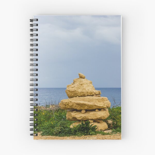 Item preview, Stacked Coastal Rocks Beside Calm Sea Under Cloudy Sky With Green Vegetation And Wildflowers designed and sold by Nmallia.