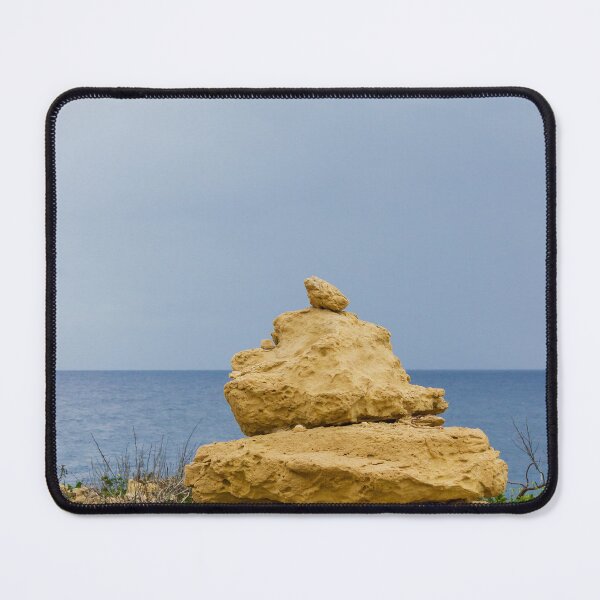 Item preview, Stacked Coastal Rocks Beside Calm Sea Under Cloudy Sky With Green Vegetation And Wildflowers designed and sold by Nmallia.
