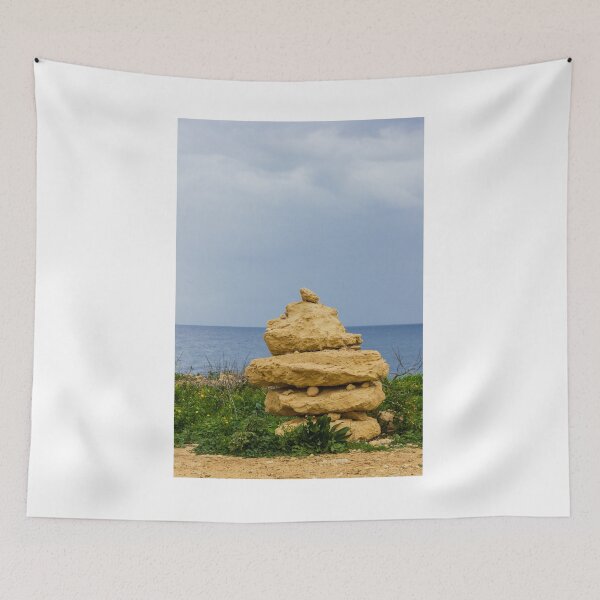 Item preview, Stacked Coastal Rocks Beside Calm Sea Under Cloudy Sky With Green Vegetation And Wildflowers designed and sold by Nmallia.