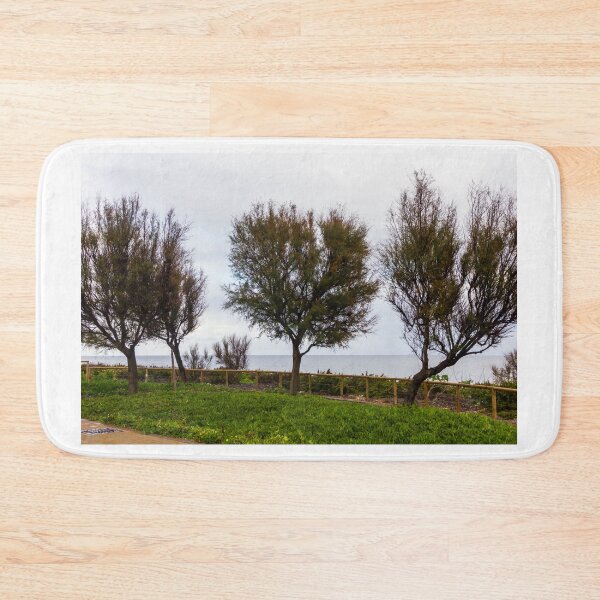 Item preview, Wind-Swept Coastal Trees Along a Green Seaside Path Overlooking Calm Ocean Horizon on Cloudy Day designed and sold by Nmallia.