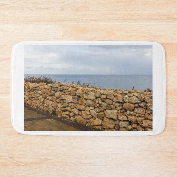 Item preview, Rugged Stone Wall Along Coastal Promenade Overlooking Calm Sea Under Overcast Sky designed and sold by Nmallia.