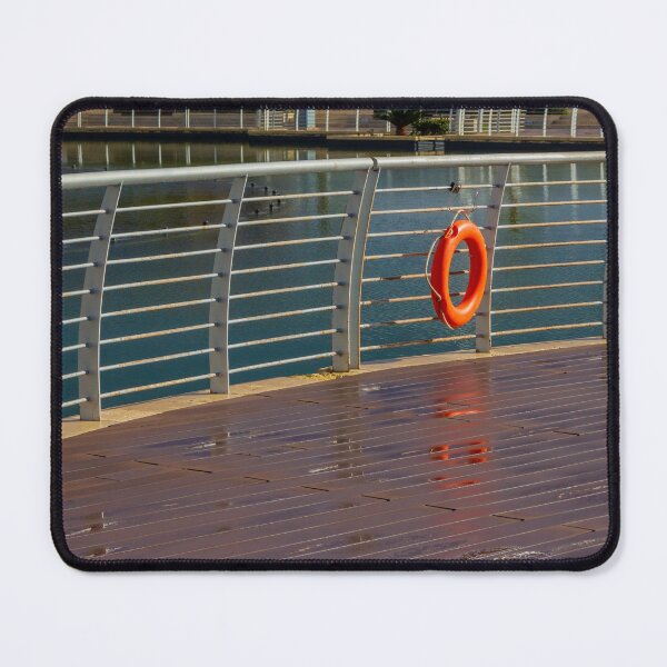 Item preview, Orange Lifebuoy Hanging on Metal Railing Along Waterfront Boardwalk Promenade Over Calm Harbor Water designed and sold by Nmallia.