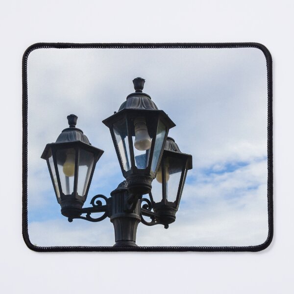 Item preview, Vintage Three-Head Street Lamp Lantern On Decorative Lamppost Against Blue Cloudy Sky designed and sold by Nmallia.