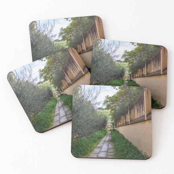 Item preview, Tranquil Paved Garden Path Along Stone Wall Surrounded By Green Foliage And Olive Trees designed and sold by Nmallia.