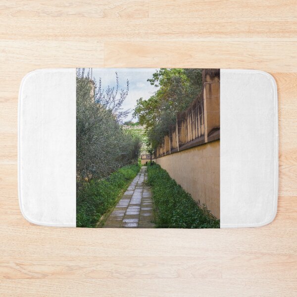 Item preview, Tranquil Paved Garden Path Along Stone Wall Surrounded By Green Foliage And Olive Trees designed and sold by Nmallia.