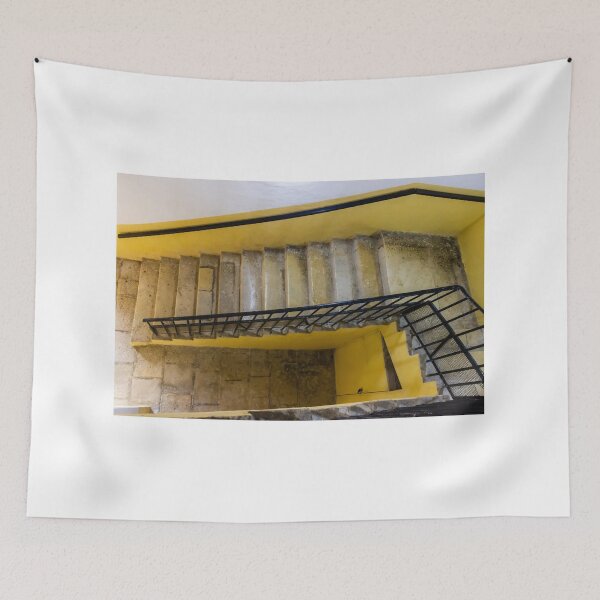 Item preview, Empty Yellow Stairwell With Worn Stone Steps And Black Metal Railing In Apartment Building designed and sold by Nmallia.