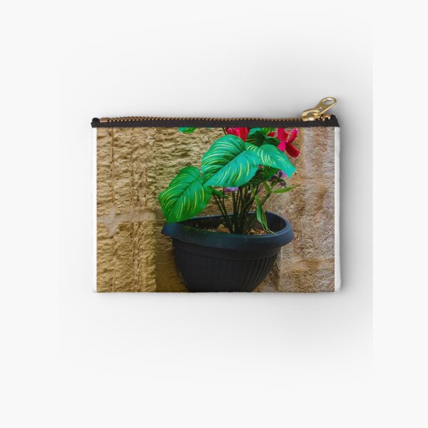 Item preview, Green Houseplant With Pink Flowers in Wall-Mounted Black Planter Against Textured Stone Wall designed and sold by Nmallia.