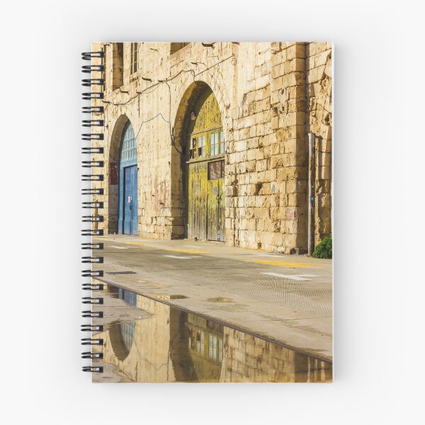 Item preview, Sunlit Old Stone Building With Arched Doors And Pavement Reflection, Weathered Yellow Door And Blue Entrance On Sunny Street designed and sold by Nmallia.
