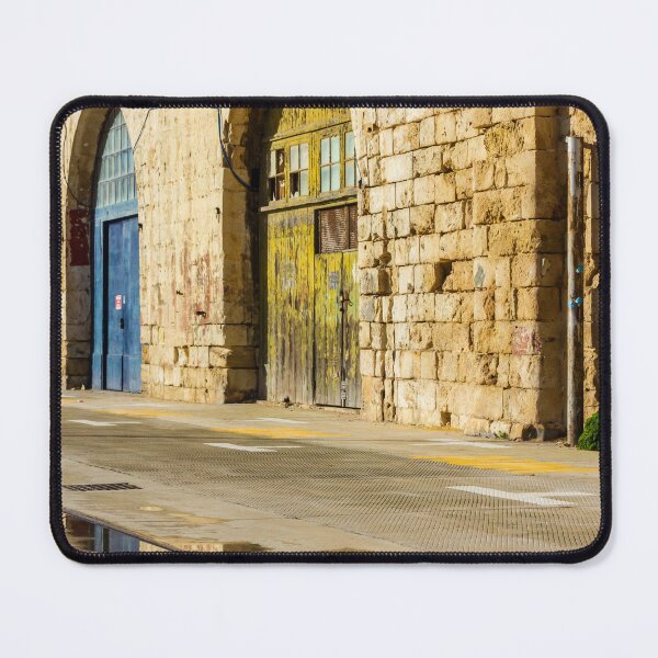 Item preview, Sunlit Old Stone Building With Arched Doors And Pavement Reflection, Weathered Yellow Door And Blue Entrance On Sunny Street designed and sold by Nmallia.