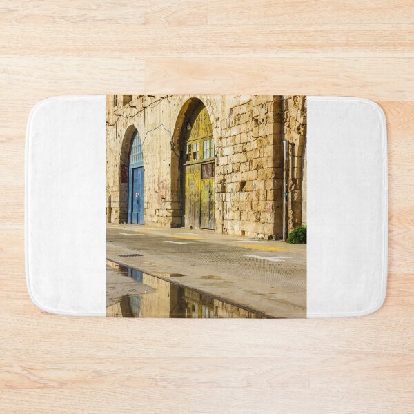 Item preview, Sunlit Old Stone Building With Arched Doors And Pavement Reflection, Weathered Yellow Door And Blue Entrance On Sunny Street designed and sold by Nmallia.