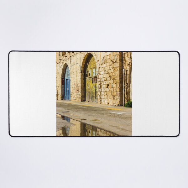 Item preview, Sunlit Old Stone Building With Arched Doors And Pavement Reflection, Weathered Yellow Door And Blue Entrance On Sunny Street designed and sold by Nmallia.