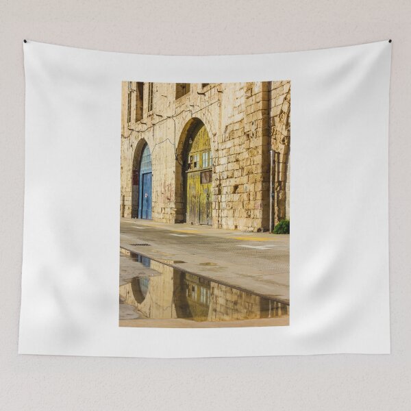 Item preview, Sunlit Old Stone Building With Arched Doors And Pavement Reflection, Weathered Yellow Door And Blue Entrance On Sunny Street designed and sold by Nmallia.